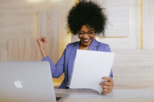 woman holding office paper sitting in front of a laptop